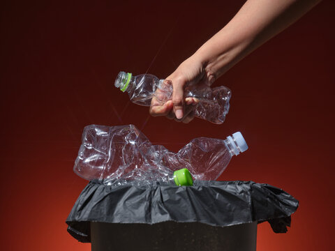 Recycling concept: hand throwing plastic bottles into trash can.