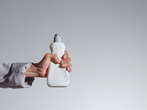Hand holding a clear plastic water bottle against a gray background.