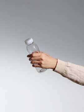 Hand holding a white cleaning product bottle on gray background