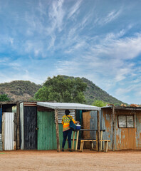 Fototapeta premium african woman worker going to work in the morning in the shanty town , south africa, shack made of corrugated sheet galvanized metal