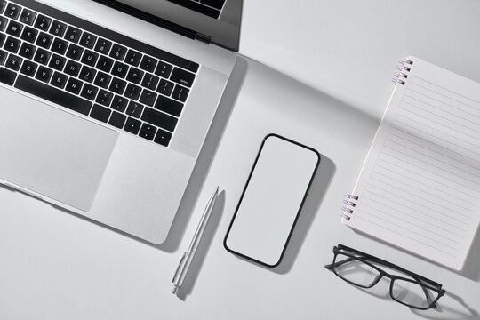 A modern workspace setup with a laptop, phone, and office supplies