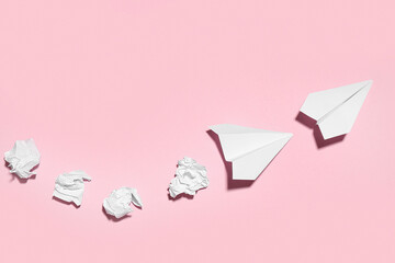 Paper planes with crumpled sheets on pink background