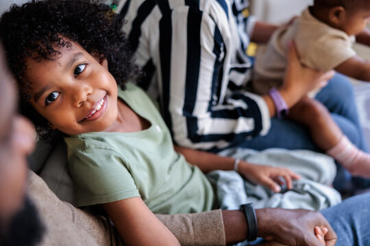 Smiling girl with family, including baby, on couch.
