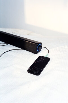 Flash on linen sheets illuminates a USB speaker and phone. 