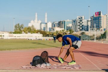 Young male athlete stretching on track in Muscat, Oman