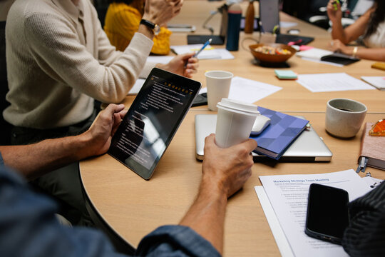 Details of hands at work in a modern office with documents and tech