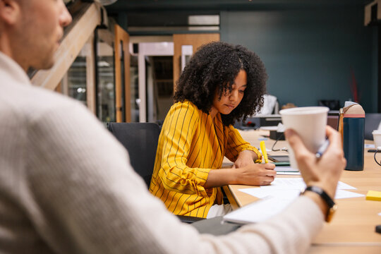 Young professional writing notes during a collaborative session