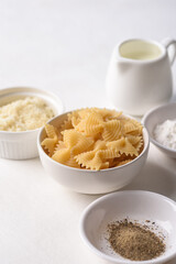 Farfalle pasta with cheese and black pepper, ingredients for Italian cooking on white background