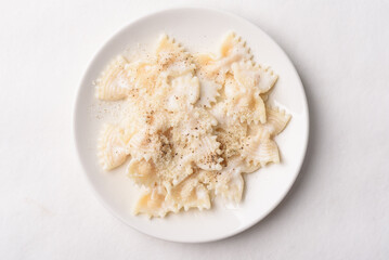 Farfalle pasta with white cream cheese sauce and black pepper, Italian food on a white plate