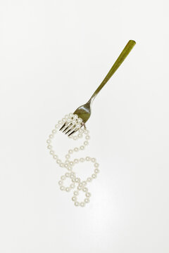 Conceptual image of eating jewellery pearls with fork cutlery & plate