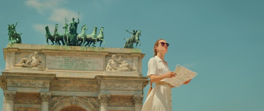 Woman exploring tourist spot reading map in front of arch monument in Milan city Italy