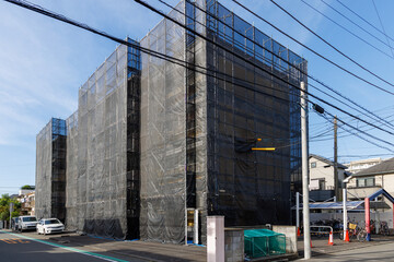 外壁工事のために黒いネットで覆われた集合住宅