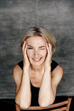 Playful adult woman winking with hands on face