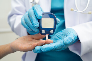 Asian doctor using digital glucose meter for check sample blood sugar level to treatment diabetes.