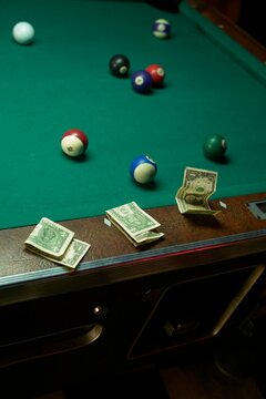 Pool Table With Money Placed Near Cue Balls in a Game Area