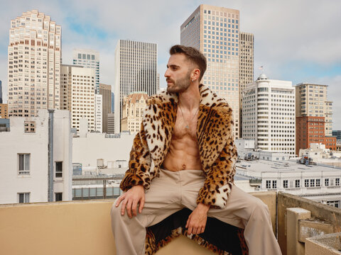 Man Posing on Rooftop in Leopard Print Coat in Urban Setting