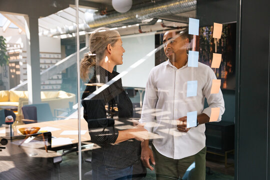 Two coworkers discussing topics using sticky notes in a modern room