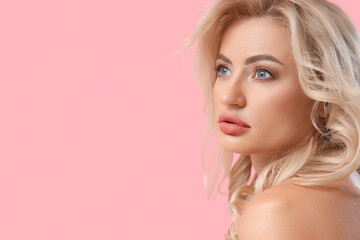 Naklejka premium Pretty young woman with curly blonde hair on pink background, closeup