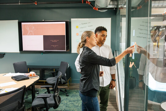 Colleagues Brainstorming With Post-Its on a Glass Wall