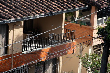 Sunny balcony view with plants and wires in an urban setting