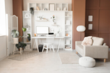 Blurred view of modern office with workplace, shelving units and sofa