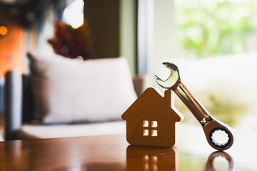 Small house model with wrench on wooden table, concept of home repair, maintenance service, housing...