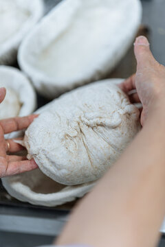 Hands placing bread dough into proofing basket