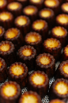 Baked caneles arranged on perforated tray