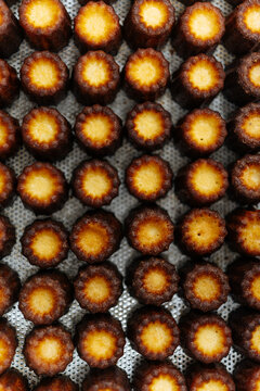Baked caneles arranged in rows on metal tray