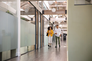 Two people walking in a modern office interior with glass partitions