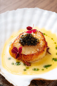 Seared scallop with caviar and microgreens in shell