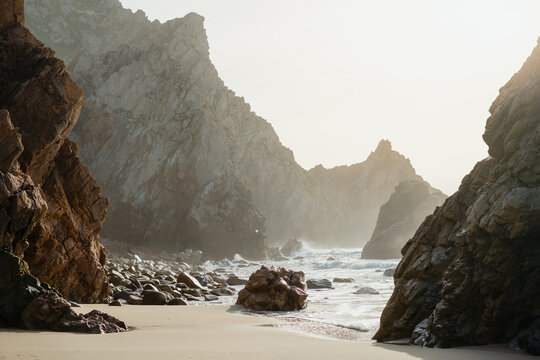 rocky cliffs and waves crashing on a secluded sandy beach