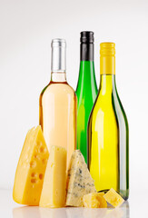 Fototapeta premium Assorted cheeses and wine bottles on white background