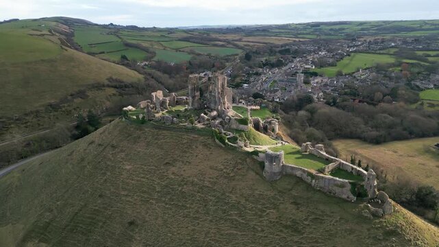 Aerial Drone Footage of Corfe Castle in England &mdash; Historic Medieval Ruins, Scenic Countryside Views, and Dramatic Ancient Landmark Rising Above the Landscape