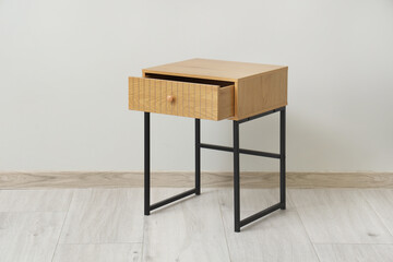 Wooden bedside table near grey wall in room