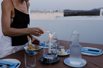 Unknown woman lighting decorative candles on centerpiece of a table