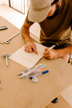 A carpenter marking measurements and drawing plans for furniture