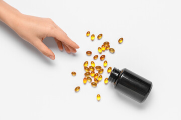 Female hand with jar of vitamin E capsules on white background