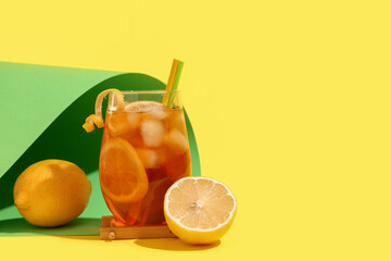 Fototapeta premium Glass of tasty cold ice tea with lemon on yellow background, closeup