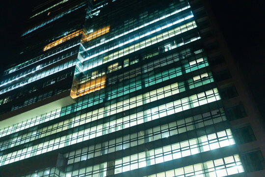 Bright Office Building Illuminated at Night in a City Skyline