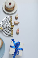 Hanukkah celebration with menorah, dreams, gifts and traditional donuts on a white background.
