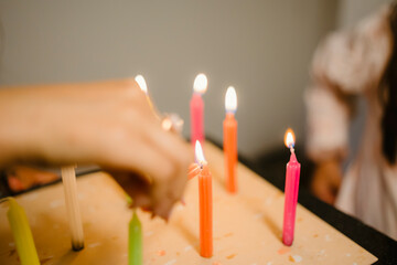 Hand lighting colorful birthday candles 