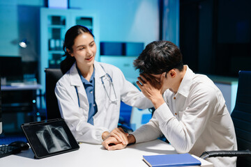 Asian doctor comforting stressed patient in hospital office, showing compassion, empathy, and emotional support during mental health consultation.
