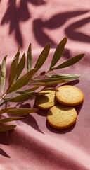 Delicate cookies on a pink surface with olive leaves, sunlight and shadows.
