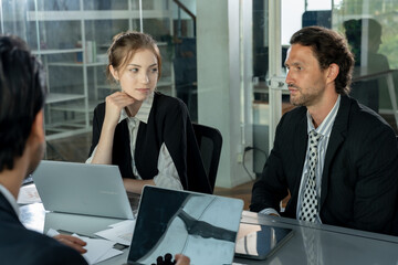 Focused multicultural office team analyzing data during meeting using laptop documents business charts while caucasian woman and man observe and discuss project strategy together