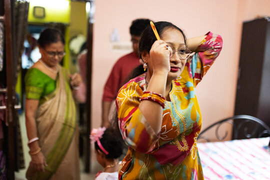 Indian woman arranging hair with comb inside home