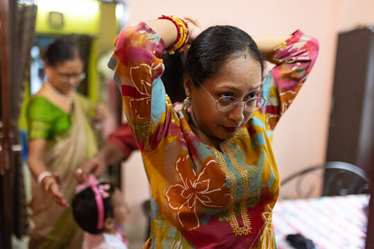 Indian woman arranging hair with comb inside home