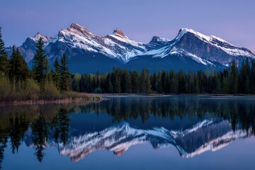 Idyllic Mountain Range Reflected in Calm Lake at Dusk with Lush Green Trees and Snowy Peaks Under a Soft Blue and Pink Sky