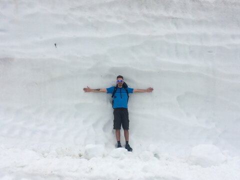 Man with arms wide against alpine snow wall