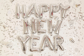 Silver confetti and balloons reading happy new year